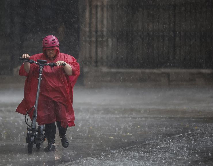 Unha persoa camiña baixo a choiva nun día de frío e treboadas 