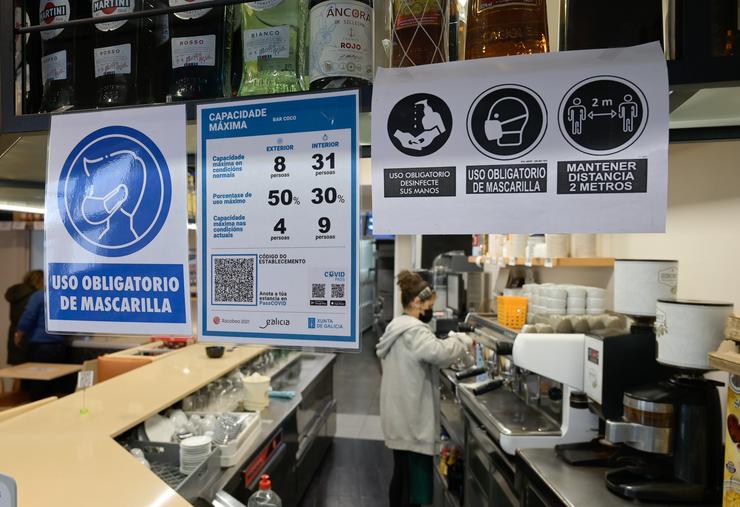 Varios carteis onde se mostra o aforamento e o código QR na porta dun restaurante na Coruña a 12 de marzo de 2021. M. Dylan - Europa Press 