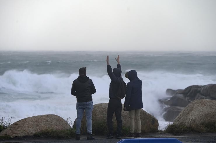 Tres novos miran e fotografan o mar embravecido, a 4 de novembro de 2023, na Coruña / M. Dylan - Arquivo