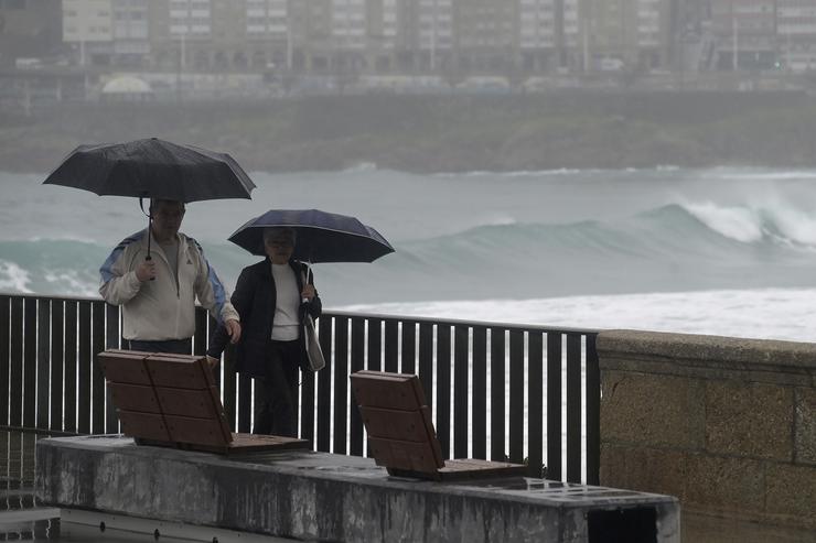 Dúas persoas camiñan cun paraugas á beira da praia do Orzán, a 22 de xaneiro de 2024, A Coruña / M. Dylan - Arquivo