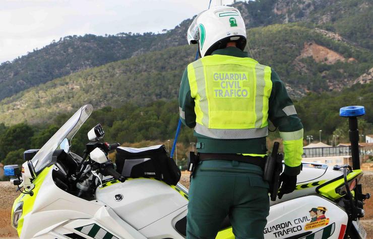 Arquivo - Un axente da Garda Civil de Tráfico, de costas, nunha estrada xunto á súa moto e unha montaña ao fondo.. GARDA CIVIL - Arquivo / Europa Press