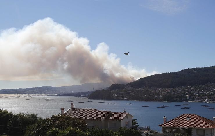 Un helicóptero á beira dunha columna de fume no incendio de Moaña 