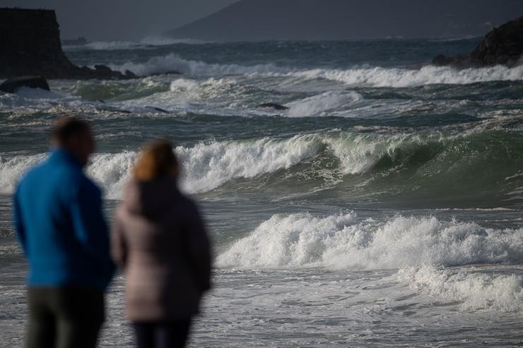 Dúas persoas observan o mar con ondas na praia da Lanzada, a 5 de novembro de 2023, no Grove / Elena Fernández - Arquivo