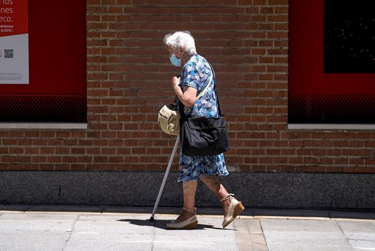  Unha anciá con máscara camiña pola rúa axudada dunha muleta.. A. Pérez Meca - Europa Press - Arquivo