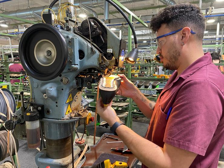 Un mozo traballador dentro dunha fábrica de calzado 