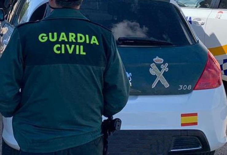 Un axente da Garda Civil de costas e xunto a un vehículo oficial do corpo 