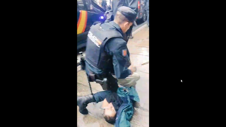 Un policía antidisturbio detén a un manifestante pro palestino que protestaba diante dun Burger Kin en Compostela