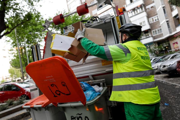 Arquivo - Un operario de recollida de residuos protexidos con máscara extrae caixas de cartón dun cubo de lixo para triturarlas nun camión de lixo durante o seu traballo de limpeza nunha rúa da capital durante o día 33 do estado de alarma, e. Jesús Hellín - Europa Press - Arquivo 