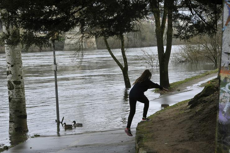 Arquivo - Unha muller sóbese a unha zona segura debido á inundación do río Miño na zona da praia da Antena, en Ourense, Galicia (España), a 11 de febreiro de 2021. O volume do Miño ao seu paso pola cidade presentou onte un elevado volume, de. Rosa Veiga - Europa Press - Arquivo / Europa Press