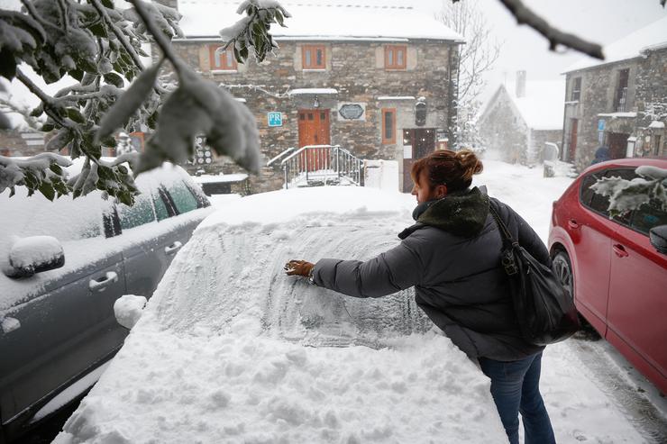 Unha muller limpa a neve do seu coche, a 9 de decembro de 2024, en Pedrafita do Cebreiro, Lugo, Galicia (España). Un total de 12 comunidades autónomas están hoxe en risco (alerta amarela) por neve, choivas, ondada e fortes refachos de vento, en especia. Carlos Castro - Europa Press / Europa Press