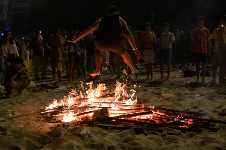 Unha persoa salta unha fogueira durante a Noite de San Xoán, na praia de Riazor, a 23 de xuño de 2023, na Coruña / M. Dylan - Arquivo