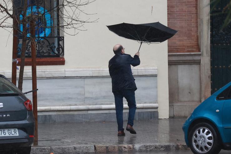 Unha persoa protéxese da choiva co seu paraugas 