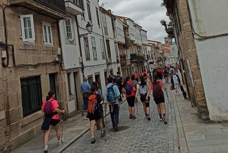 Peregrinos baixan polo medio da Rúa de San Pedro, en Santiago de Compostela 