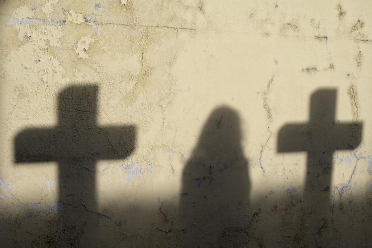 Sombra dunha muller e dúas cruces no cemiterio de San Amaro 