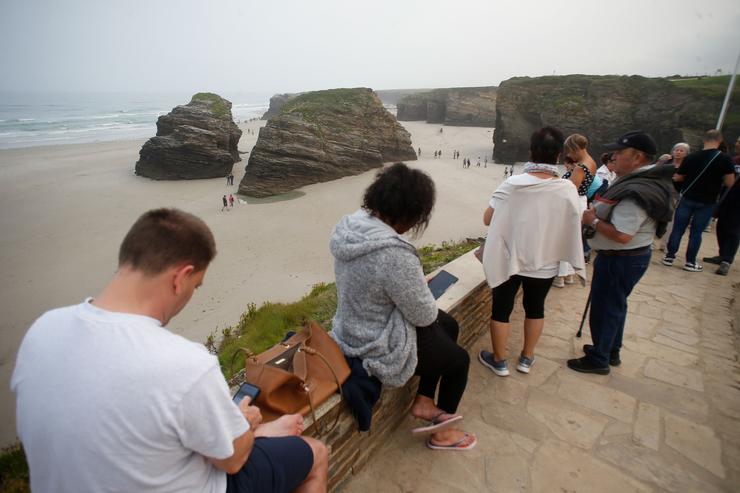 Varias persoas pasean durante a baixamar na praia das Catedrais. Carlos Castro - Europa Press 