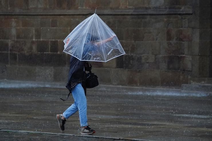 Unha persoa camiña cun paraugas durante o paso da borrasca Aline, a 19 de outubro de 2023, en Santiago de Compostela 