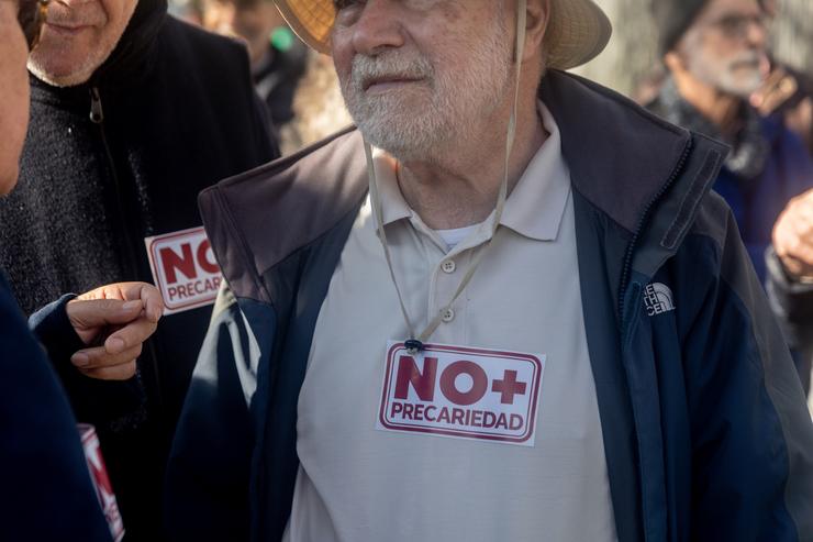 Un home leva un adhesivo na que se le 'Non + precariedade' durante unha concentración convocada pola plataforma RMI O teu Dereito (Renda Mínima de Inserción), fronte ao Ministerio de Inclusión.. Ricardo Rubio - Europa Press 